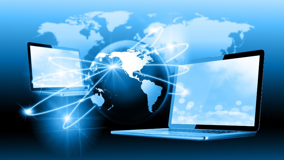 Két laptop látható, amelyek globális kapcsolatok szimbólumaként világítanak, háttérben a Föld térképével.