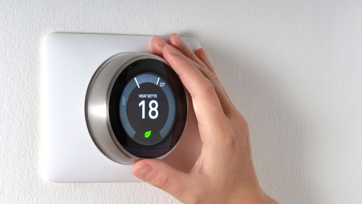 Egy kéz éppen egy Computherm termosztátot állít be, amely 18 fokra van állítva.