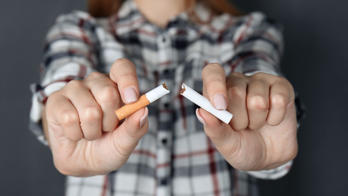 Egy nő két kezében egy törött és egy ép cigarettát tart, jelezve a dohányzás abbahagyását.