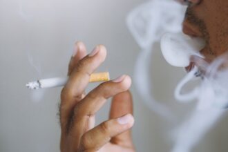 Egy férfi cigarettázik, füstfelhőkkel körülvéve, amely a stresszoldás szimbóluma.
