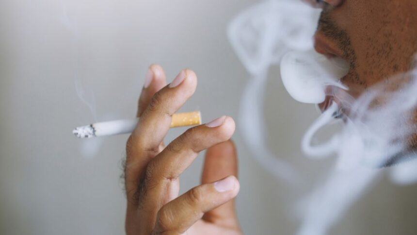 Egy férfi cigarettázik, füstfelhőkkel körülvéve, amely a stresszoldás szimbóluma.