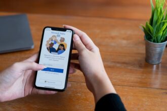Egy kéz tart egy okostelefont, amelyen a Microsoft Teams bejelentkezési képernyője látható.