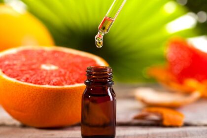 Egy üveg grapefruit illóolaj, cseppentővel, friss grapefruit mellett.