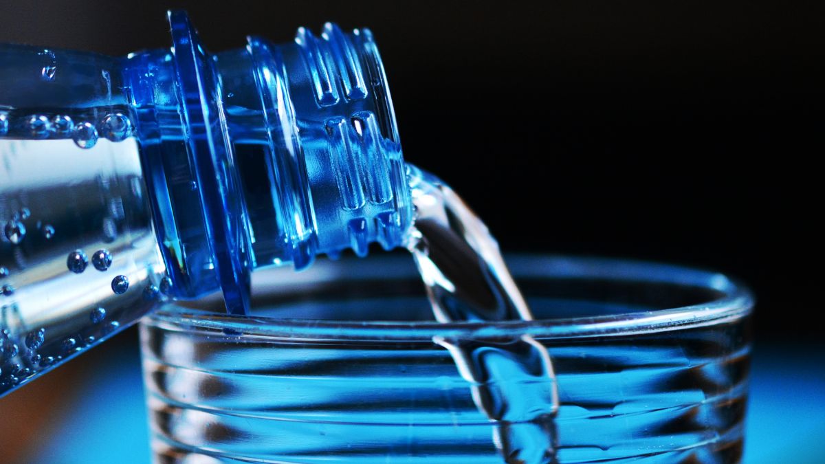 Egy palack hidrogénnel dúsított víz öntése egy átlátszó pohárba.