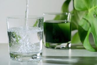 Egy frissítő, buborékos ital folyik egy pohárba, mellette zöld klorofill tartalmú ital.