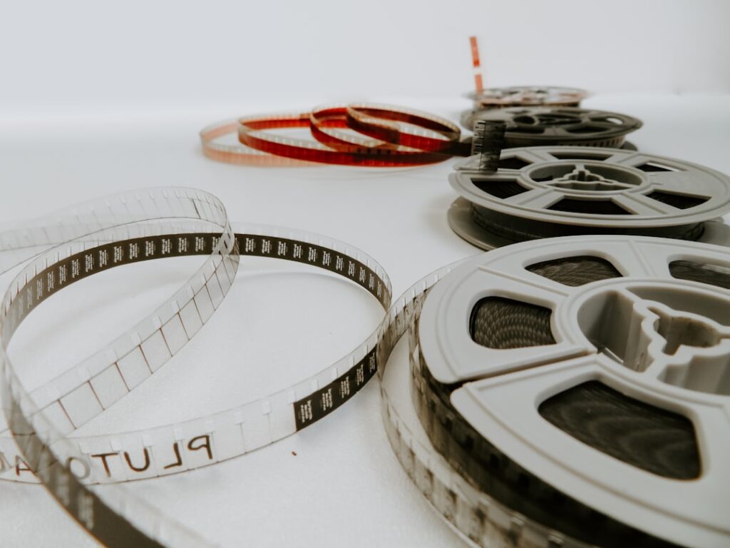 Filmtekercsek sorakoznak, különböző színű és méretű szalagokkal, a múlt filmes világát idézve.