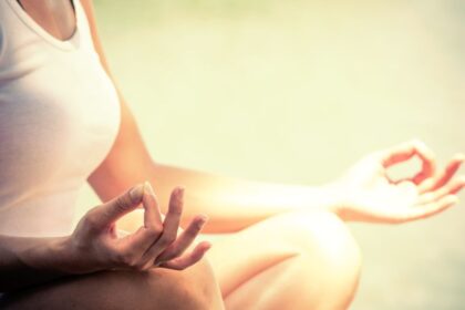 Egy nő meditál a természetben, lótuszülésben, békés környezetben.