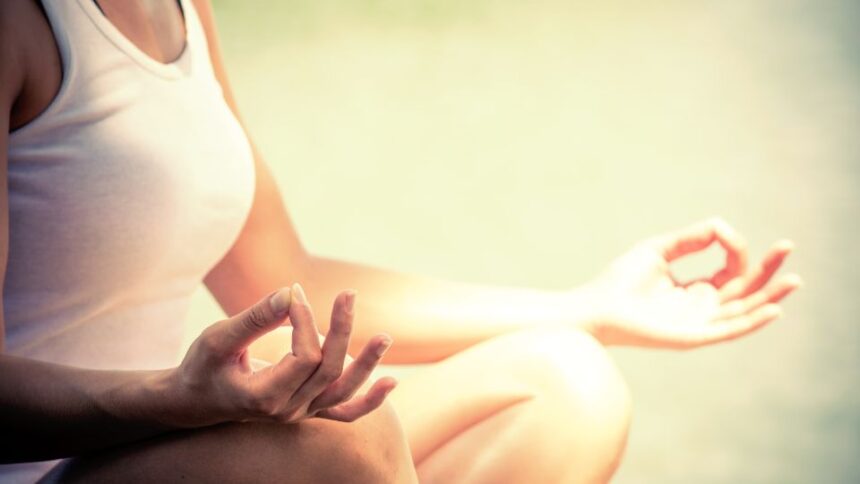 Egy nő meditál a természetben, lótuszülésben, békés környezetben.