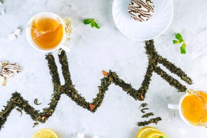 Két csésze tea, édességek és zöld tea levelek egyedi elrendezésben.