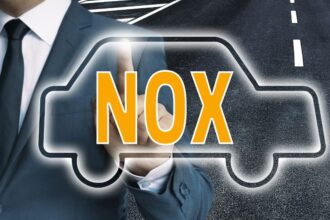 Egy öltönyös férfi mutat a NOx szóra, amely egy autó körvonalában látható.