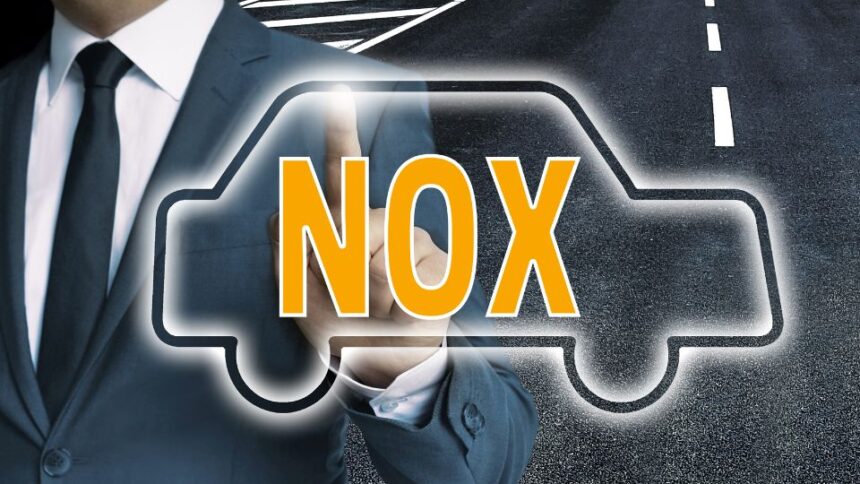 Egy öltönyös férfi mutat a NOx szóra, amely egy autó körvonalában látható.
