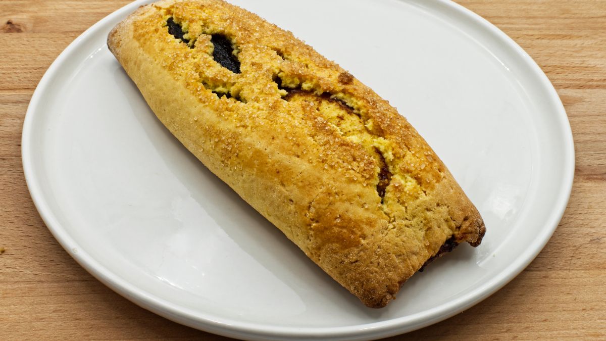 Egy frissen sült pinza, ropogós tésztával és ízletes töltelékkel, fehér tányéron.