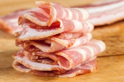Szeletelt szalonna halmokban, friss és ízletes megjelenésben, fából készült deszkán.