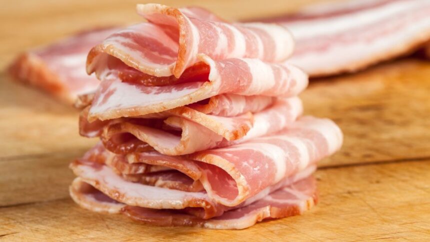 Szeletelt szalonna halmokban, friss és ízletes megjelenésben, fából készült deszkán.