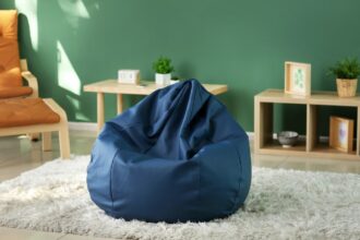Kék babzsákfotel egy világos szobában, zöld fal előtt, kényelmes pihenéshez.