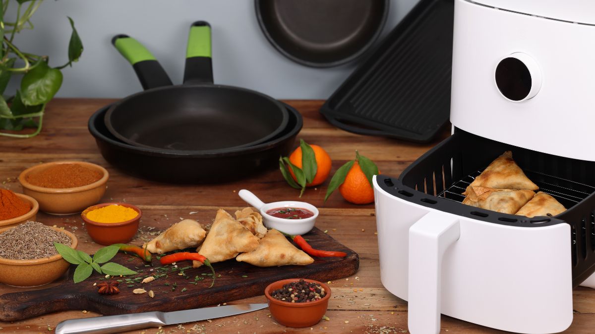 Forrólevegős fritőz, mellette fűszerek és kész ételek, mint a samosa.