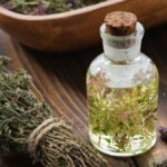 Egy üveg kakukkfű illóolaj, mellette szárított kakukkfű ágak.
