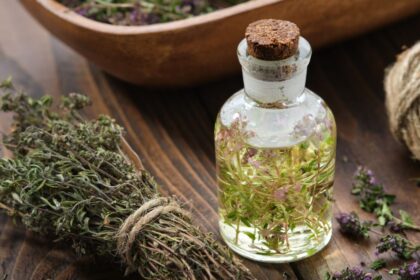 Egy üveg kakukkfű illóolaj, mellette szárított kakukkfű ágak.