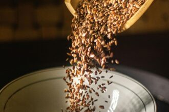Lenmagpehely öntése egy fehér tányérba, gazdag rost- és omega-3 forrás.