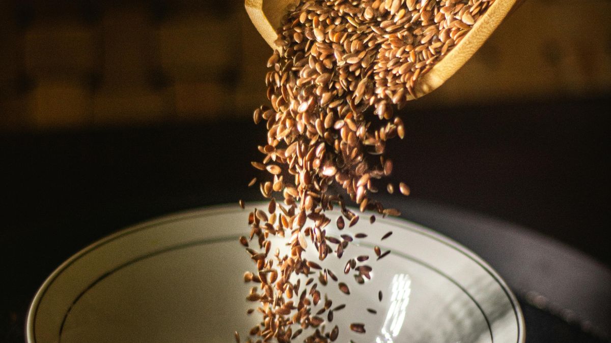 Lenmagpehely öntése egy fehér tányérba, gazdag rost- és omega-3 forrás.
