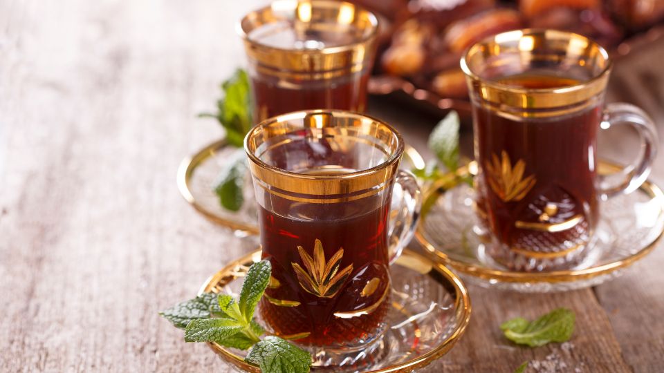 Három csésze rooibos tea, aranyozott poharakban, friss mentalevelekkel díszítve.