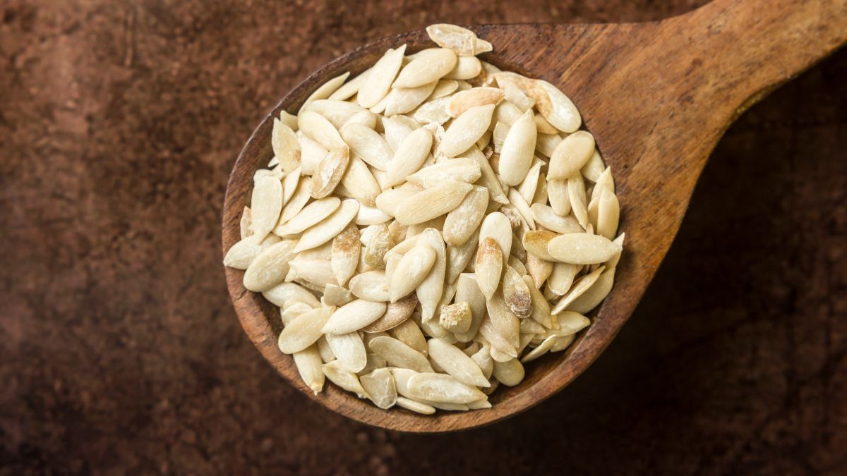 Egy fából készült kanálban sárgadinnye magok láthatók, amelyek tápanyagokban gazdagok.