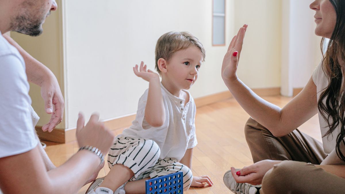 Egy kisfiú játszik a szüleivel, akik támogatóan interakcióba lépnek vele.