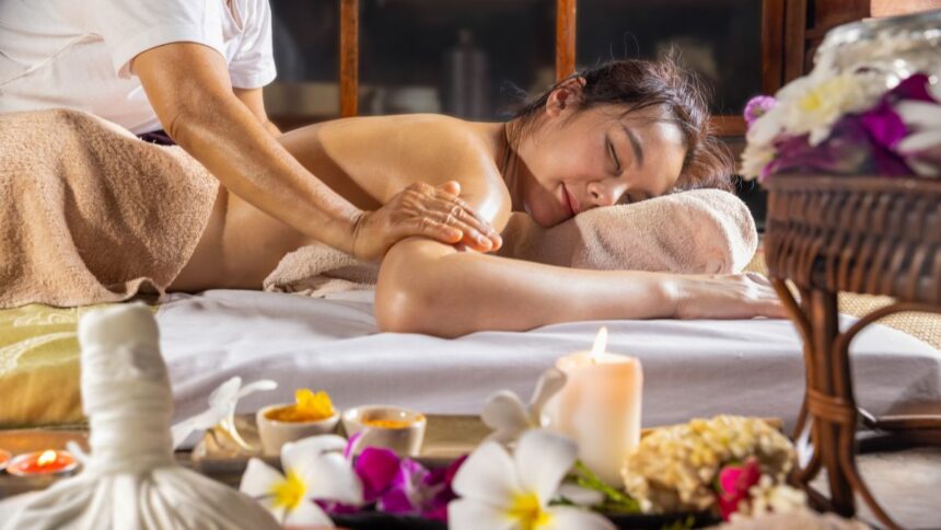 Egy nő relaxál thai olajos masszázs közben, természetes olajok és virágok környezetében.