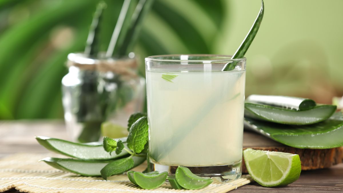 Friss aloe vera ital egy pohárban, mellette aloe levelek és lime szeletek.