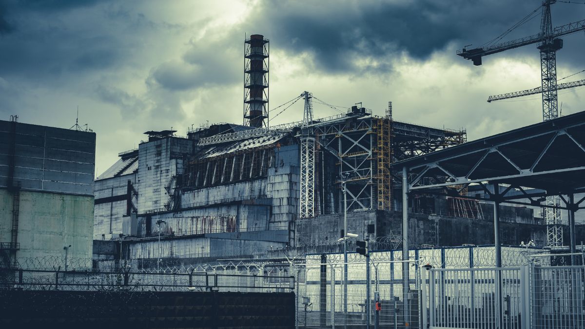 A csernobili atomerőmű romos épülete, felhős ég alatt, körülötte kerítés.