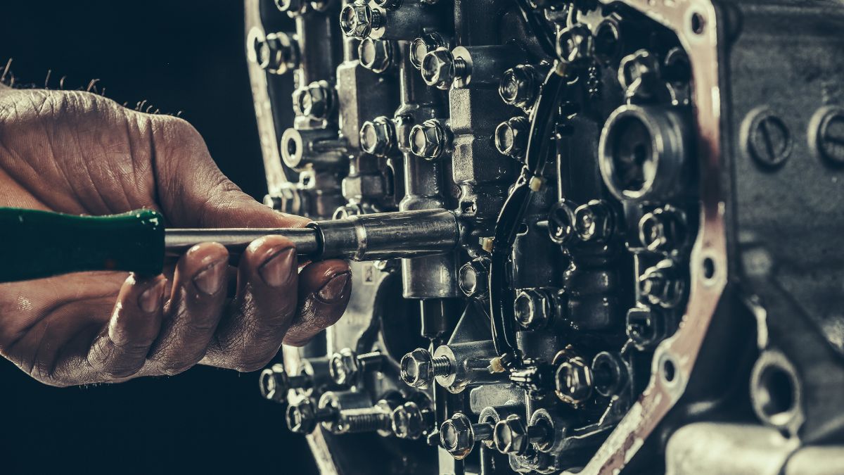 Egy kéz szerszámot tart, miközben egy CVVT motor alkatrészeit szereli.