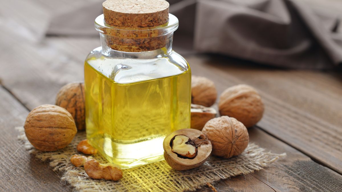 Egy üveg dióolaj, mellette diófélék, természetes környezetben.