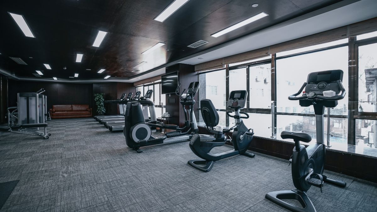 Modern edzőterem belső tér, különböző fitneszgépekkel és világos ablakokkal.