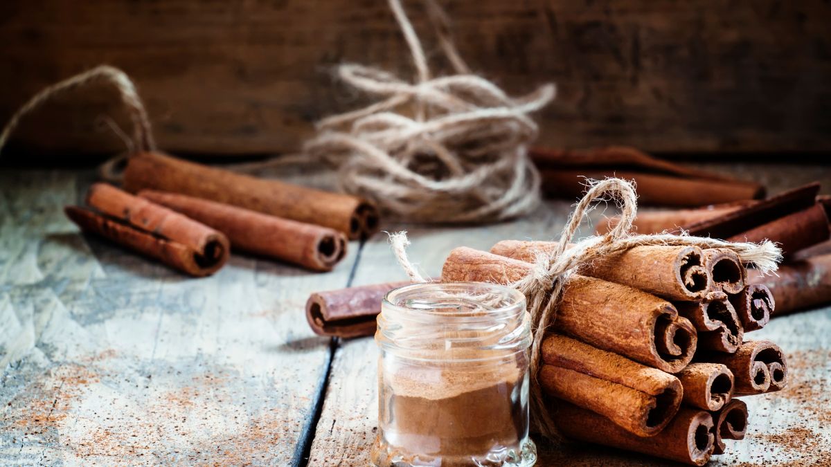 Fahéjrudak és egy kis üveg fahéjpor egy rusztikus háttér előtt.