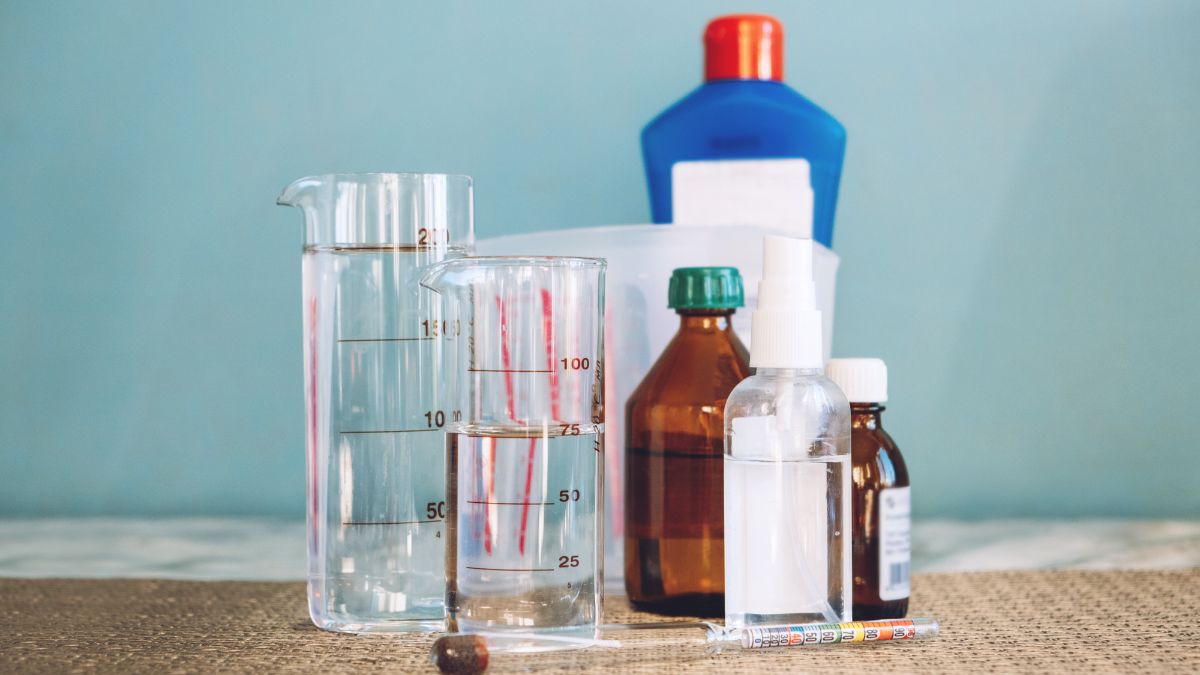 Különböző üvegek és flakonok, köztük hidrogén-peroxid, tisztítószerek és mérőedények.