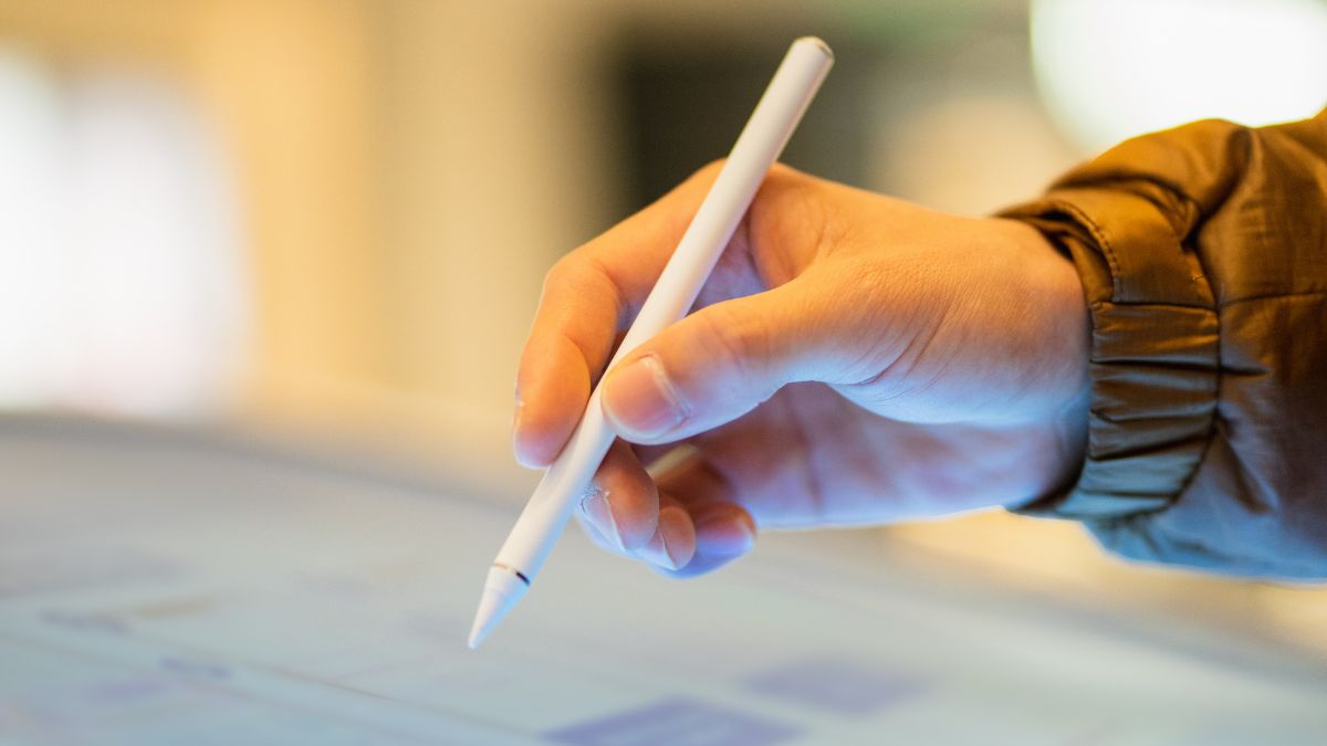 Egy kéz, amely kapacitív tollal érint egy érintőképernyőt, modern technológiát használva.