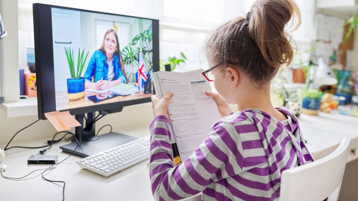 Egy gyerek online nyelvórán vesz részt, miközben könyvet olvas.