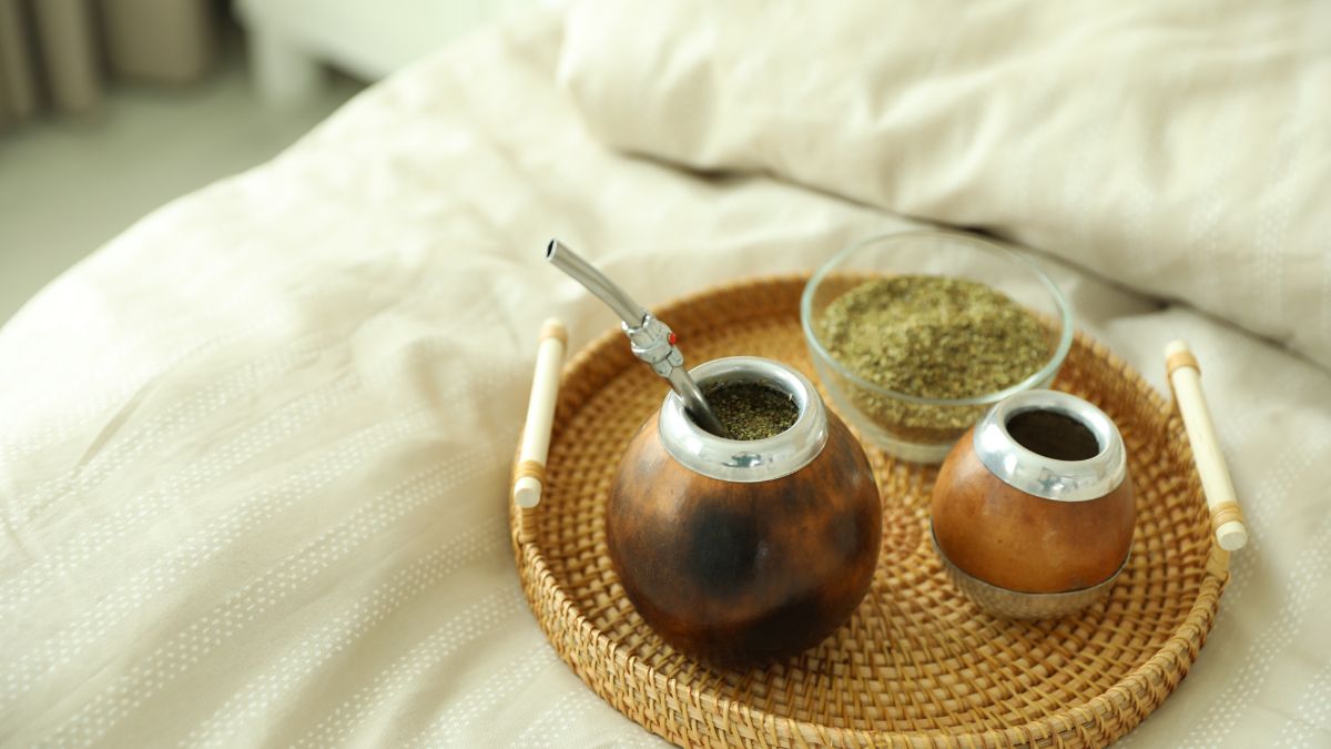 Egy tálcán mate tea készítéséhez szükséges eszközök: mate gourd, szívószál és mate levelek.