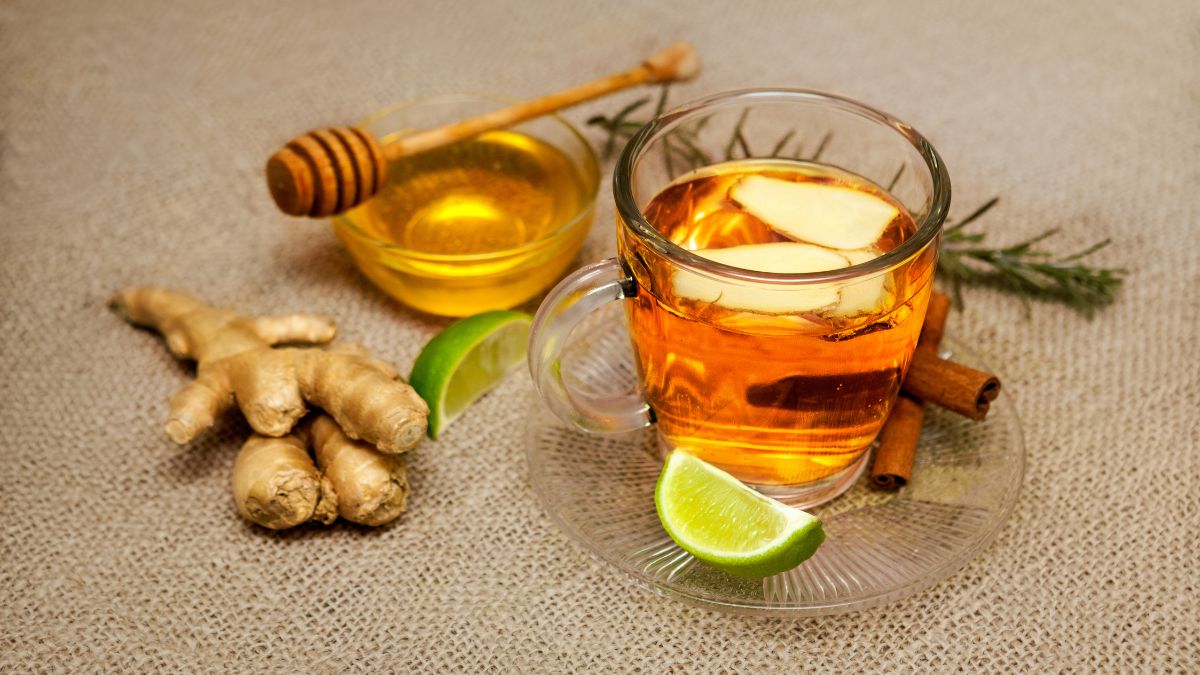 Egy pohár mézes gyömbértea lime szeletekkel, fahéjjal és mézzel, egészséges ital.