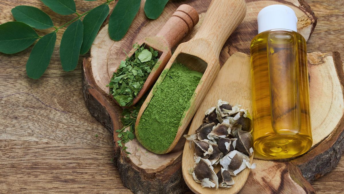 Moringaolaj, moringa levelek és magok egy fából készült tányéron, természetes környezetben.