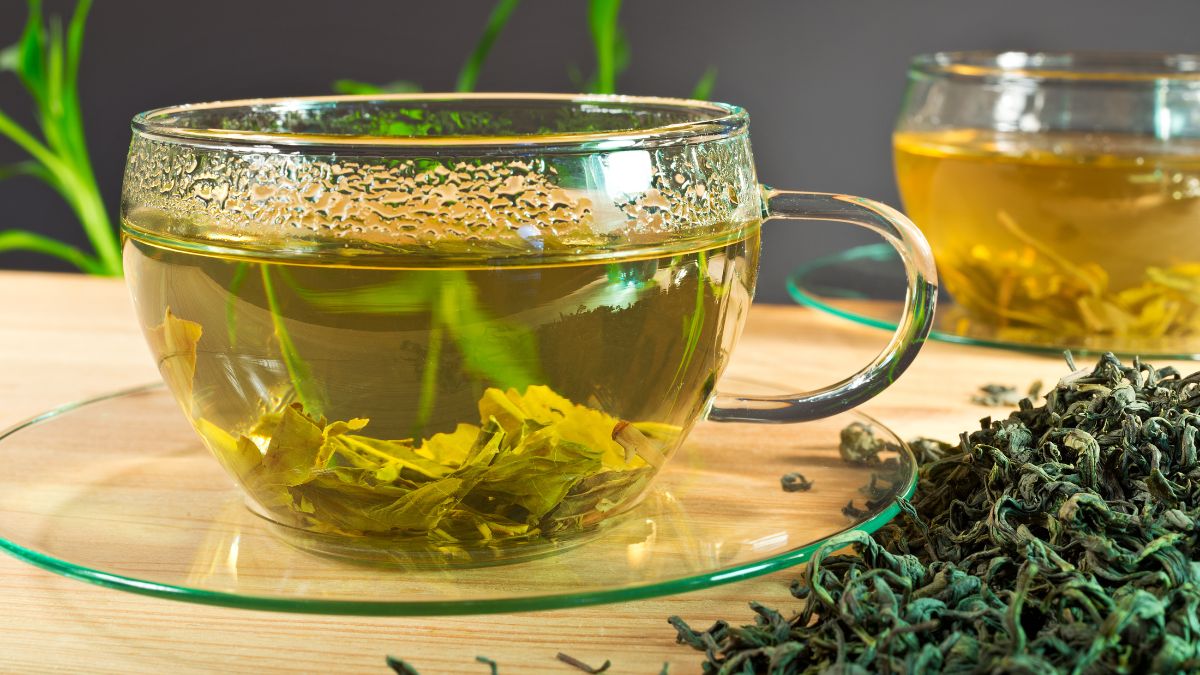 Egy átlátszó bögrében friss Tudofu tea, mellette szárított gyógynövények.