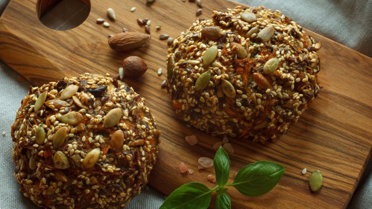 Két ízletes, magvakkal gazdag paleo kenyér egy fából készült deszkán.