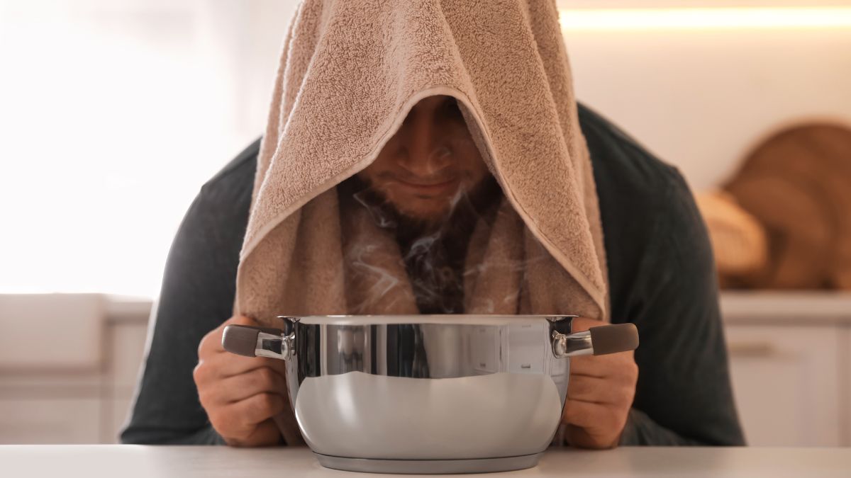 Egy férfi sós inhalálást végez, gőzölő edény fölé hajolva, törölközővel a fején.