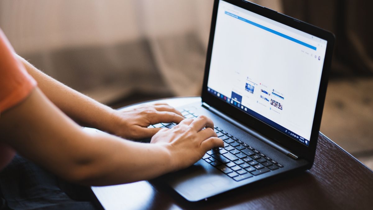 Egy kéz a laptop billentyűzetén, amelyen weboldal látható, a digitális világban való munkavégzés közben.