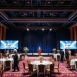 Elegáns céges rendezvény díszített asztalokkal és vetítővel.