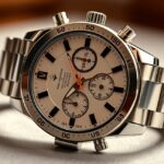 Kronográf karóra részletes nézete, világos számlapokkal és stoppertüskékkel.