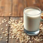 Friss zabtej egy pohárban, körülötte zabpehely és mogyorósnackek.