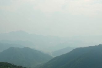 Fátyolos hegyek látképe ködben és halvány fénynél.