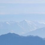 Havas hegyek és völgyek tája kék ég alatt.