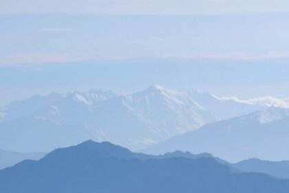 Havas hegyek és völgyek tája kék ég alatt.